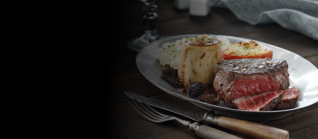 Dry-aged prime steak plated with sides on a restaurant table